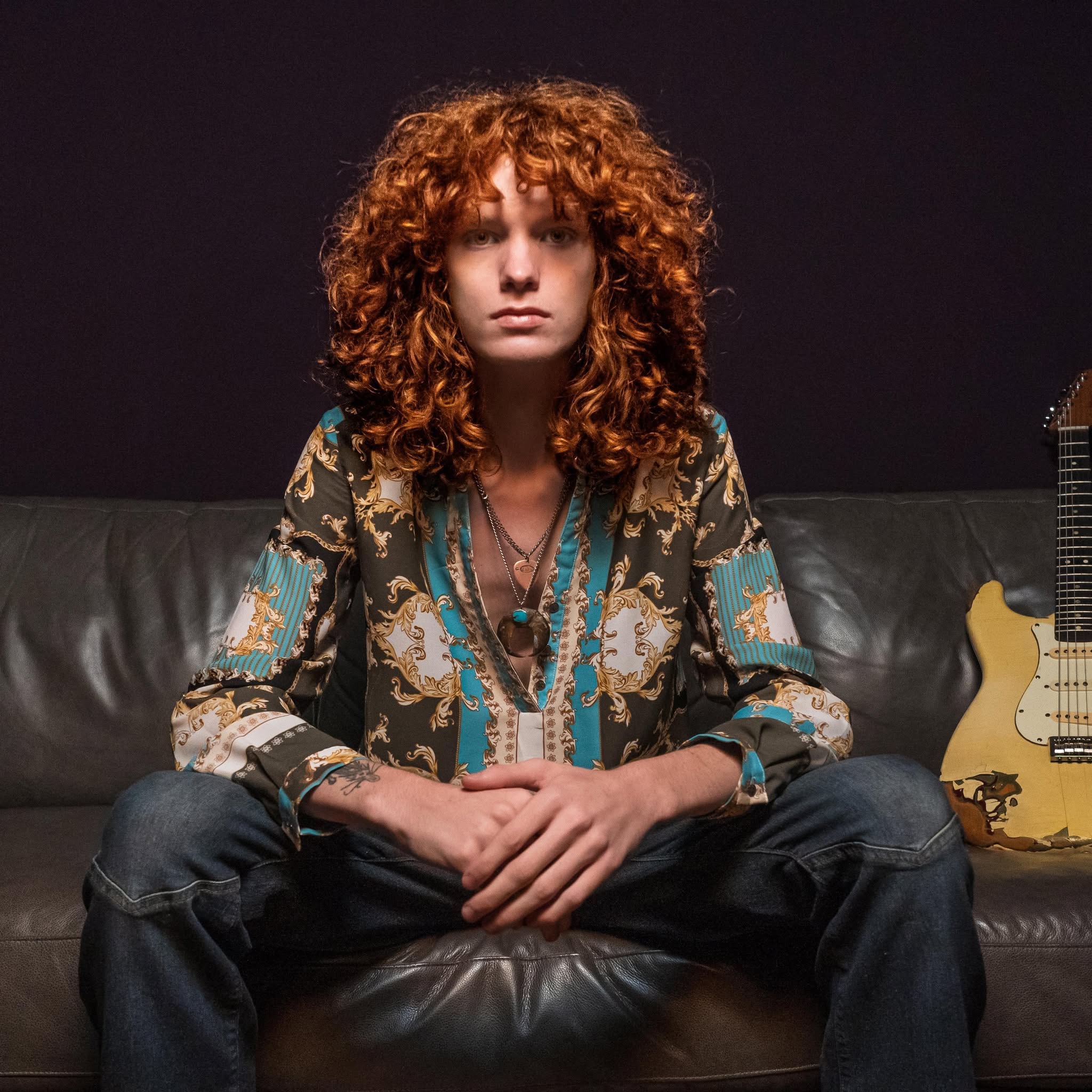 Portrait of guitarist Jesse Bennett seated with his guitar